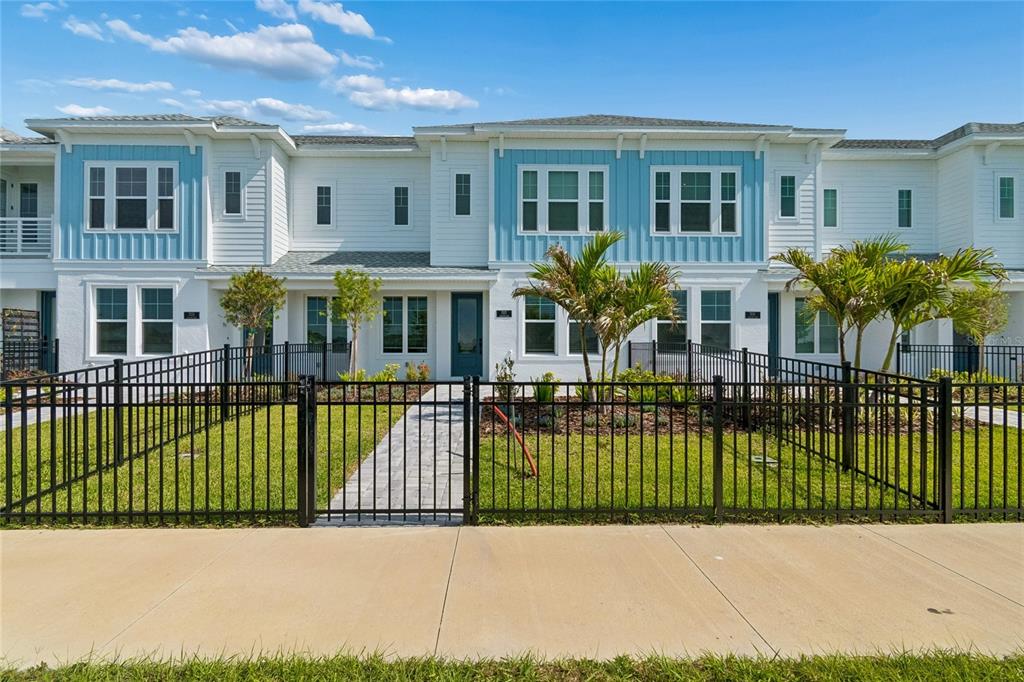 A row of two-story townhouses with blue and white siding and fenced front yards — 7227 TIDELAND LANE, SARASOTA, FL