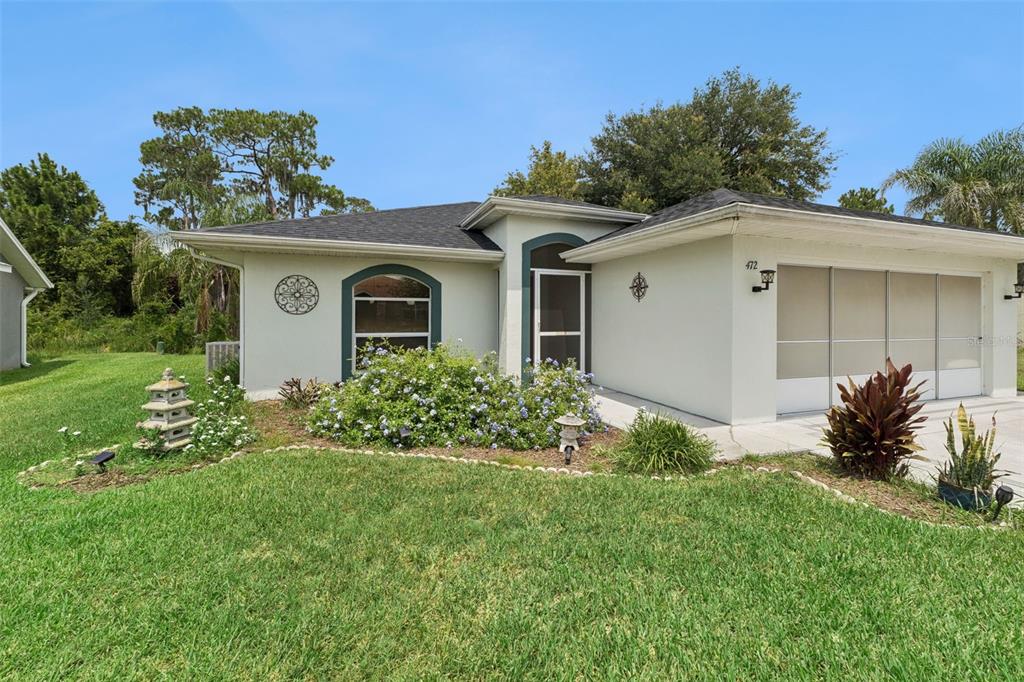 A single-story house with a white stucco exterior, a garage, and a landscaped front yard — 472 SWEETWATER WAY, HAINES CITY, FL