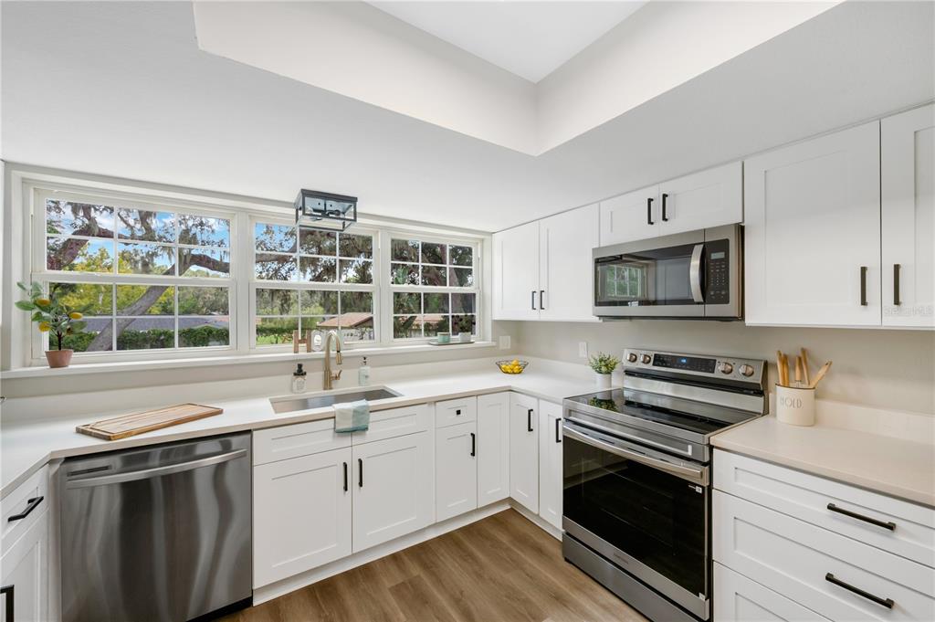 A bright kitchen features white cabinets, stainless steel appliances, and a window above the sink — 122 WINDY PLACE, BRANDON, FL
