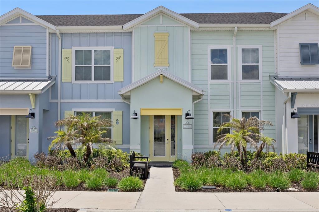 A multi-unit residential building features pastel-colored siding, yellow shutters, and a central covered entryway — 2916 ON THE ROCKS POINT, KISSIMMEE, FL