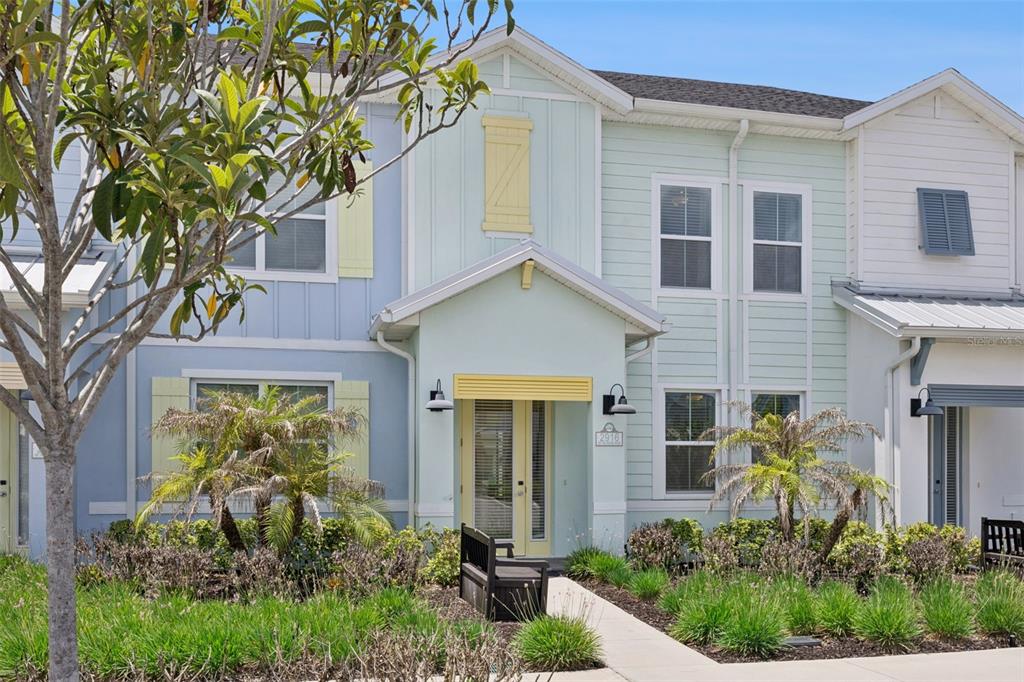 A two-story townhouse with pastel blue and green siding, yellow accents, and a front walkway — 2916 ON THE ROCKS POINT, KISSIMMEE, FL