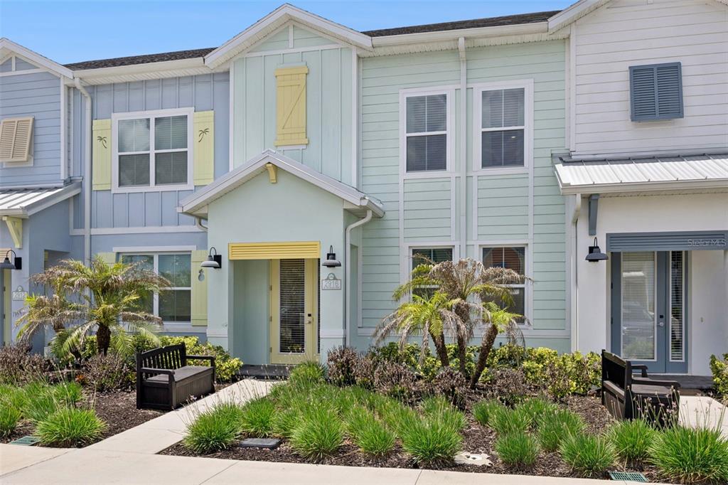 A light green and blue multi-story townhouse exterior features a front porch and small garden — 2916 ON THE ROCKS POINT, KISSIMMEE, FL