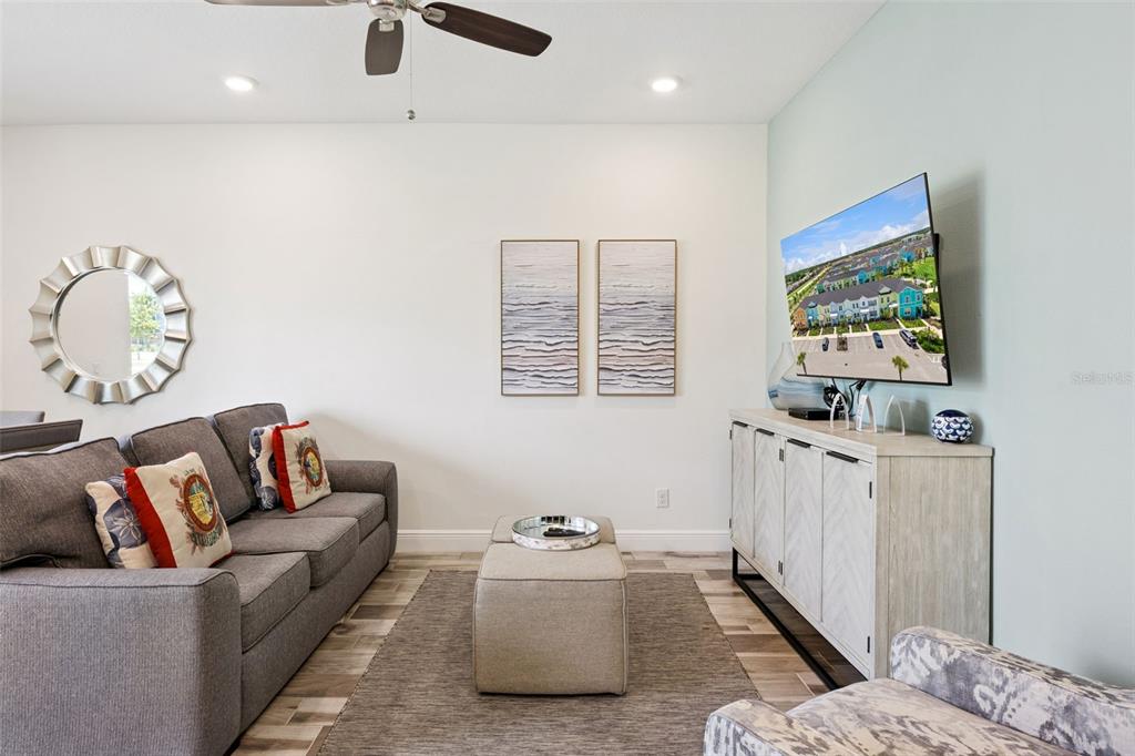 A living room features a grey sofa, a central ottoman, and a wall-mounted television — 2916 ON THE ROCKS POINT, KISSIMMEE, FL