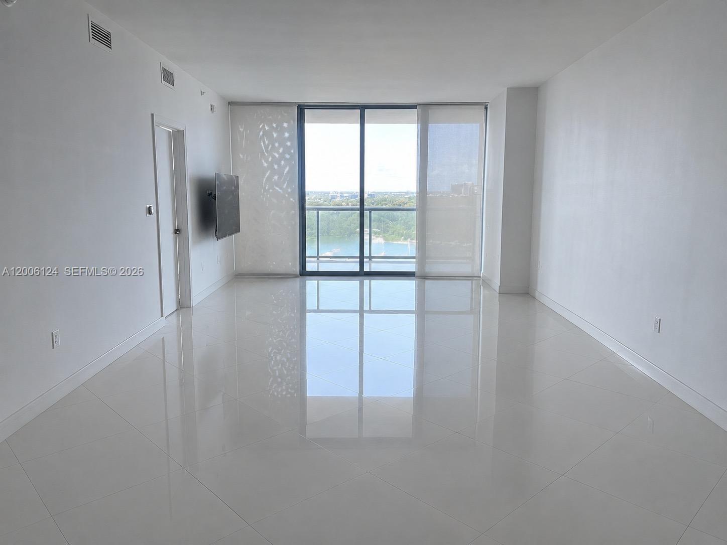 A bright, open-concept living and dining area features white walls, tile floors, and neutral furniture — 601 NE 36th St # 1404, Miami FL 33137, MIAMI, FL