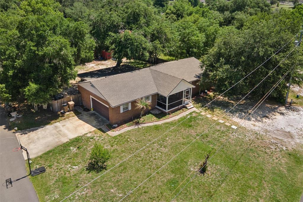 An aerial view shows a single-story brick house with a screened porch and attached garage — 14407 LAKE JUNIETTA DRIVE, TAVARES, FL