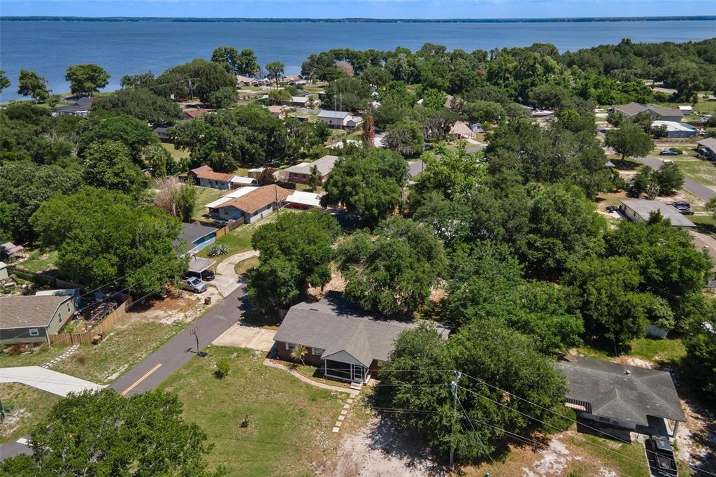 An aerial view shows a residential neighborhood with houses, trees, and a nearby lake — 14407 LAKE JUNIETTA DRIVE, TAVARES, FL