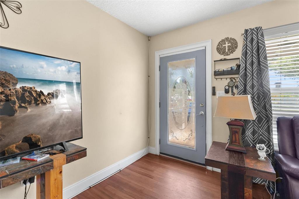 A living room features a television, a front door with glass, and wood-look flooring — 14407 LAKE JUNIETTA DRIVE, TAVARES, FL