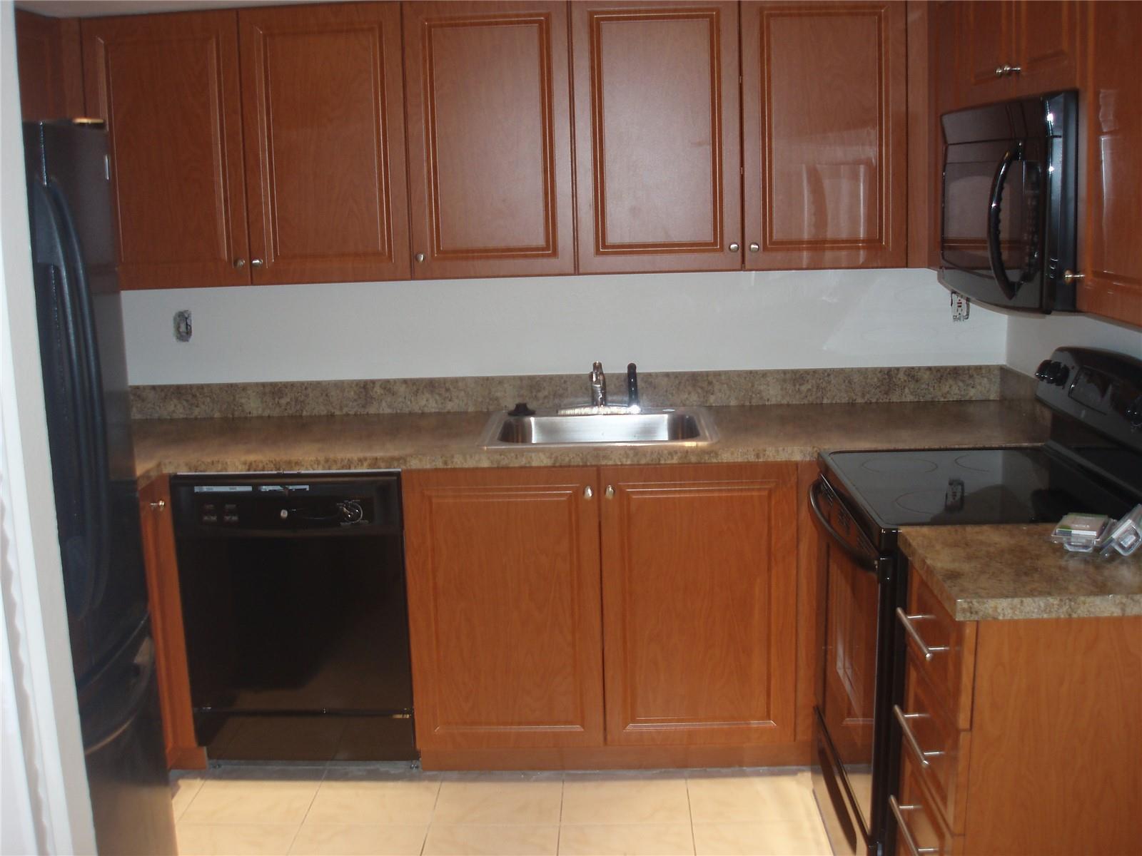 A kitchen with wood cabinets, black appliances, a stainless steel sink, and laminate countertops — 8028 SW 17th Place, Davie FL 33324, DAVIE, FL