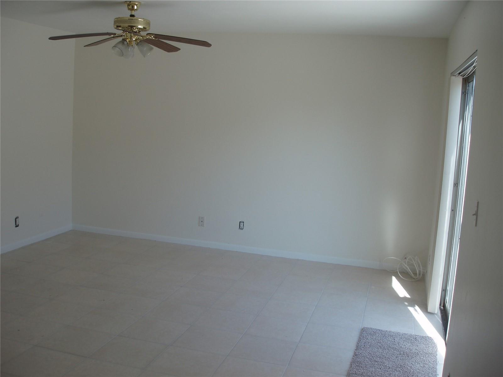 An empty room with light-colored tile flooring, a ceiling fan, and a sliding glass door — 8028 SW 17th Place, Davie FL 33324, DAVIE, FL