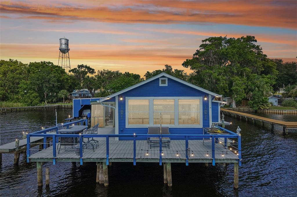 A blue house on stilts sits over the water with a wooden deck and walkway — 21 S LAKE STREET, CRESCENT CITY, FL
