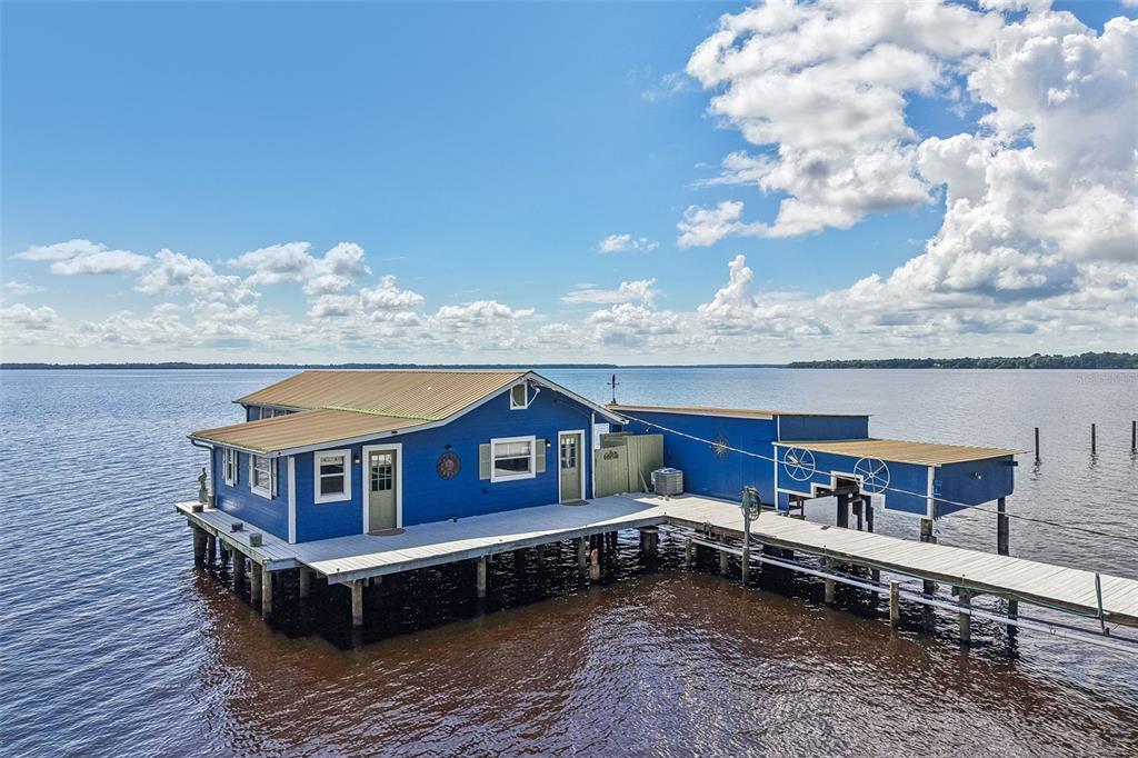 An aerial view of a blue house on stilts surrounded by a large body of water — 21 S LAKE STREET, CRESCENT CITY, FL
