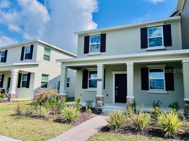 Two light-colored, two-story suburban houses stand side-by-side under a blue sky with clouds — 2639 CANDIED APPLE ALLEY, KISSIMMEE, FL