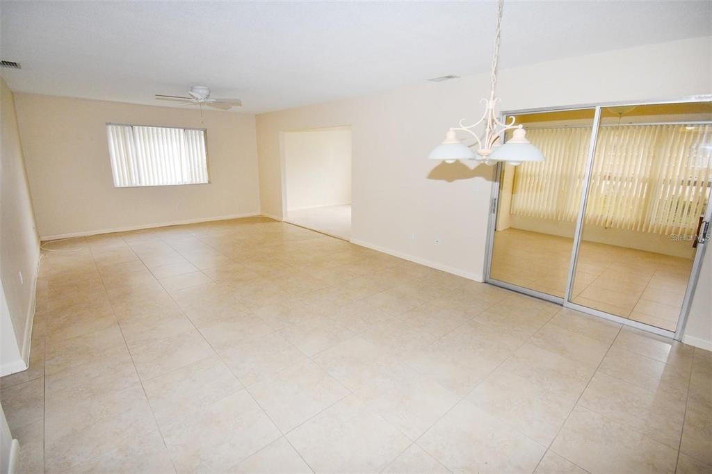 An open-concept living and dining area features light tile flooring and a sliding glass door — 3961 ASHWOOD LANE UNIT 44, SARASOTA, FL