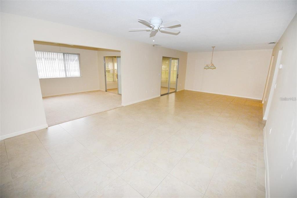 An open-concept living area features beige tile flooring, a ceiling fan, and carpeted adjacent rooms — 3961 ASHWOOD LANE UNIT 44, SARASOTA, FL
