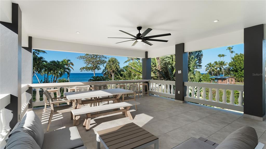 A covered outdoor patio features a dining set, lounge seating, and views of the ocean — 473 Bo. Ensenada CARR 413 KM HM 0.7, RINCON, PR
