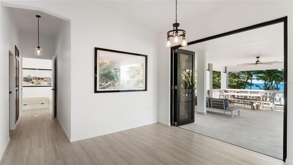 A bright room with light wood flooring opens onto a covered patio overlooking the ocean — 473 Bo. Ensenada CARR 413 KM HM 0.7, RINCON, PR