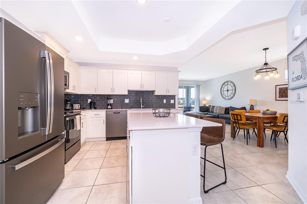 A modern kitchen with white cabinets, a large island, and stainless steel appliances — 3191 PARADOX CIRCLE UNIT 208, KISSIMMEE, FL