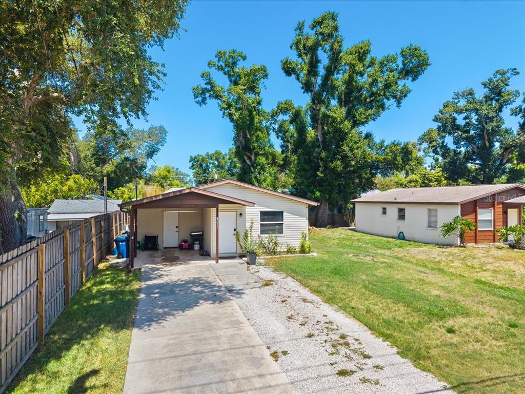 A single-story house with a carport, concrete driveway, and a wooden fence on the left — 4050 ROCKEFELLER AVENUE, SARASOTA, FL