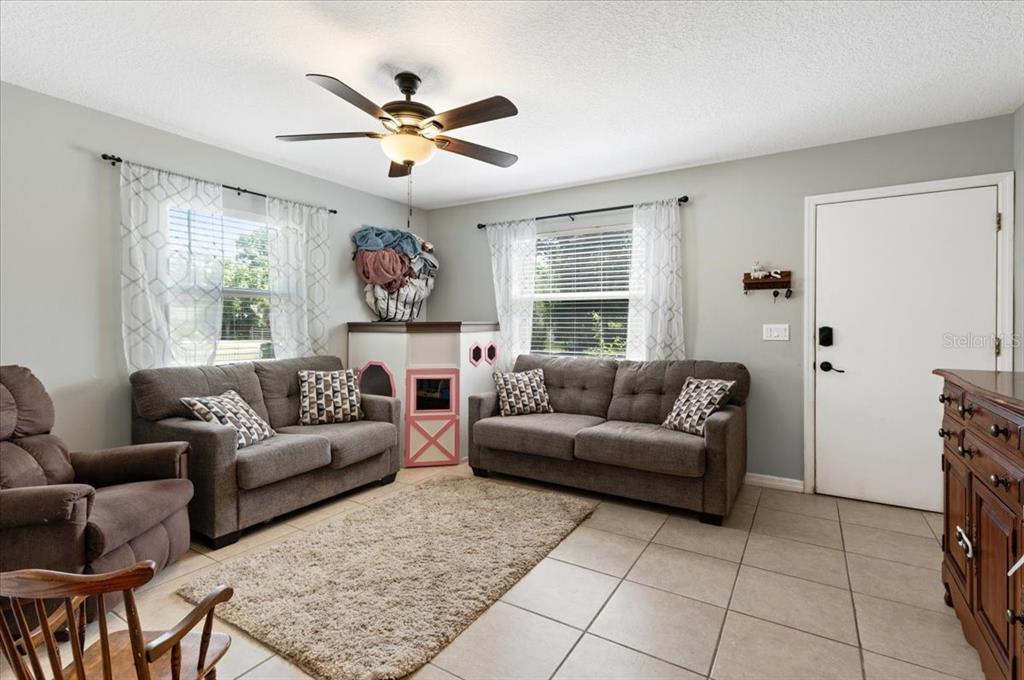 A living room features two gray sofas, a ceiling fan, and tile flooring — 4050 ROCKEFELLER AVENUE, SARASOTA, FL