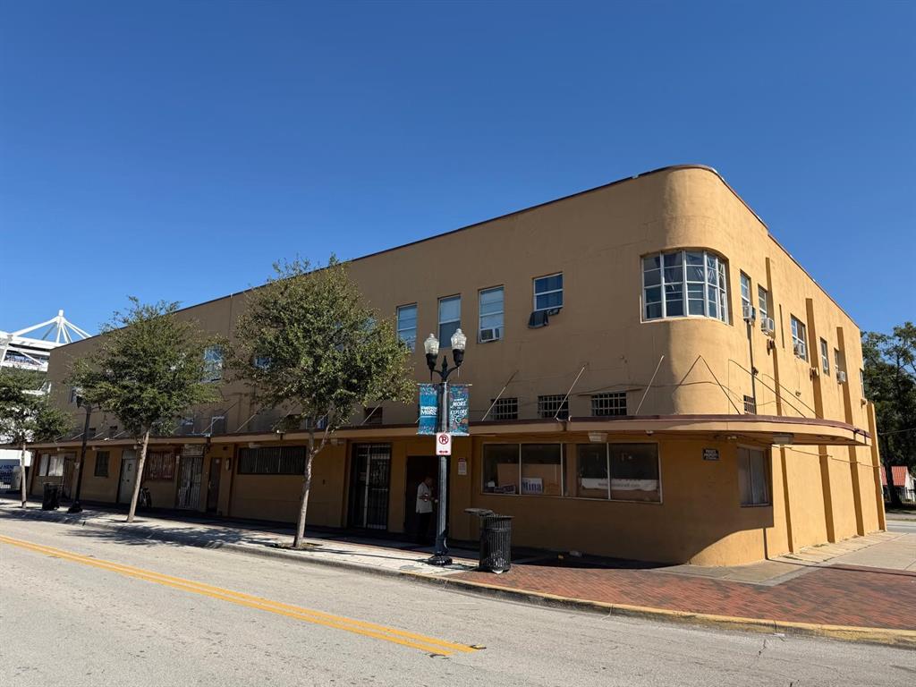 A two-story, tan-colored commercial building with a curved corner and street-level storefront windows — 221 S PARRAMORE AVENUE UNIT 7A, ORLANDO, FL