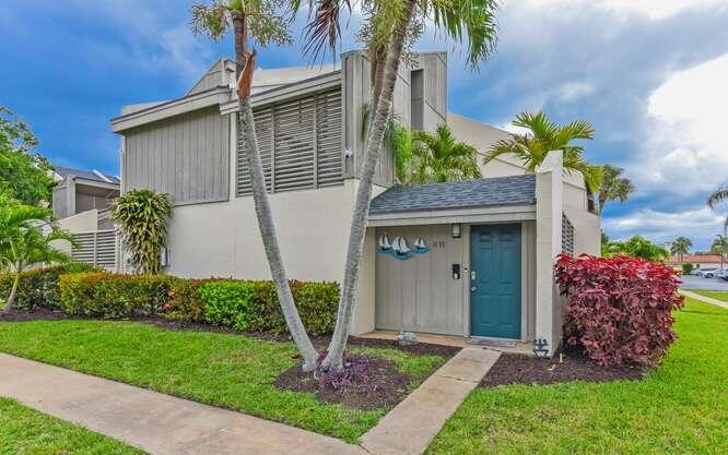 A two-story townhouse with a teal front door, palm trees, and a landscaped yard — 1605 S Us Highway 1 # 9h, Jupiter FL 33477, JUPITER, FL