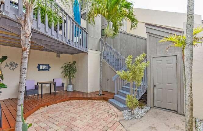 A patio area features a wooden deck, brick pavers, outdoor seating, and a wooden staircase — 1605 S Us Highway 1 # 9h, Jupiter FL 33477, JUPITER, FL