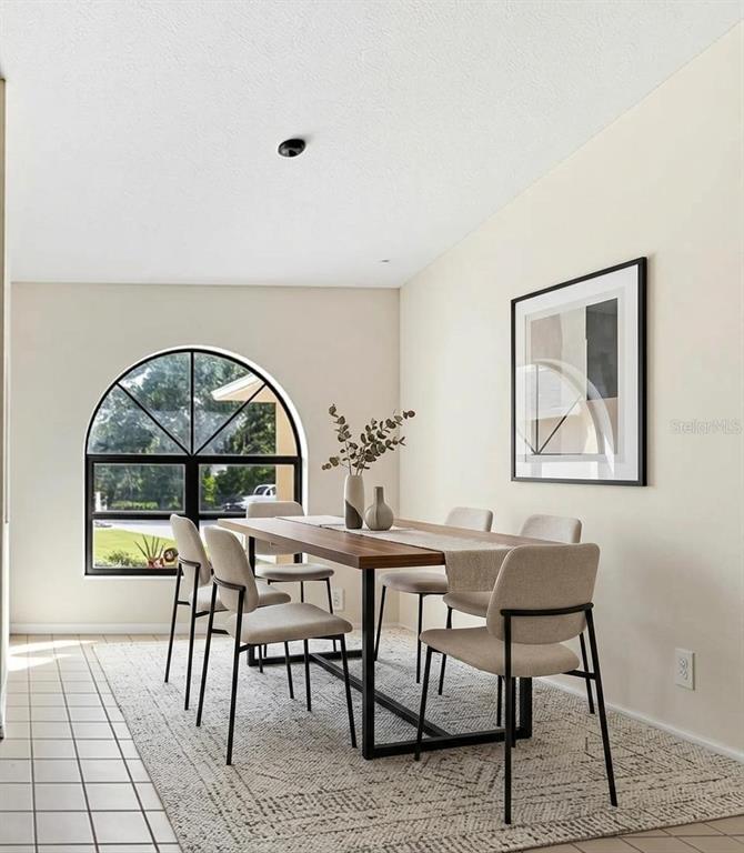 A dining room features a wooden table, six chairs, an arched window, and a rug — 8432 PALM LAKES COURT, SARASOTA, FL