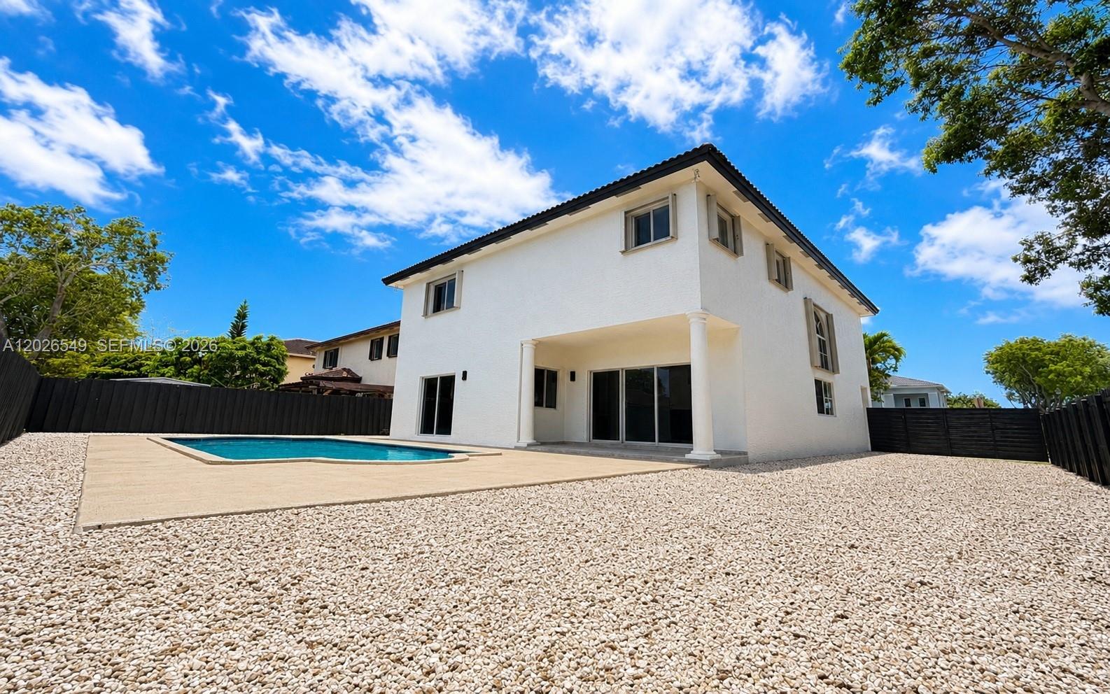 A two-story white house features a swimming pool and a gravel backyard under a blue sky — 14407 SW 158th Path, Miami FL 33196, MIAMI, FL