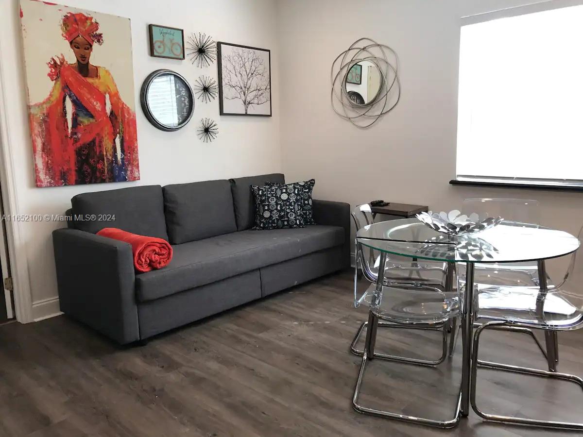 A living room features a gray sofa, a glass dining table, and various wall decorations — 2615 Collins Ave # 24, Miami Beach FL 33140, MIAMI BEACH, FL