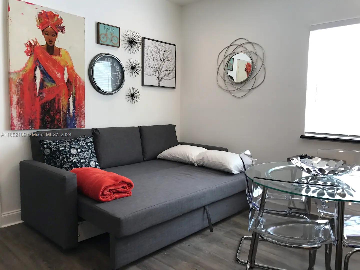 A living room features a gray sofa bed, wall art, and a glass dining table — 2615 Collins Ave # 24, Miami Beach FL 33140, MIAMI BEACH, FL