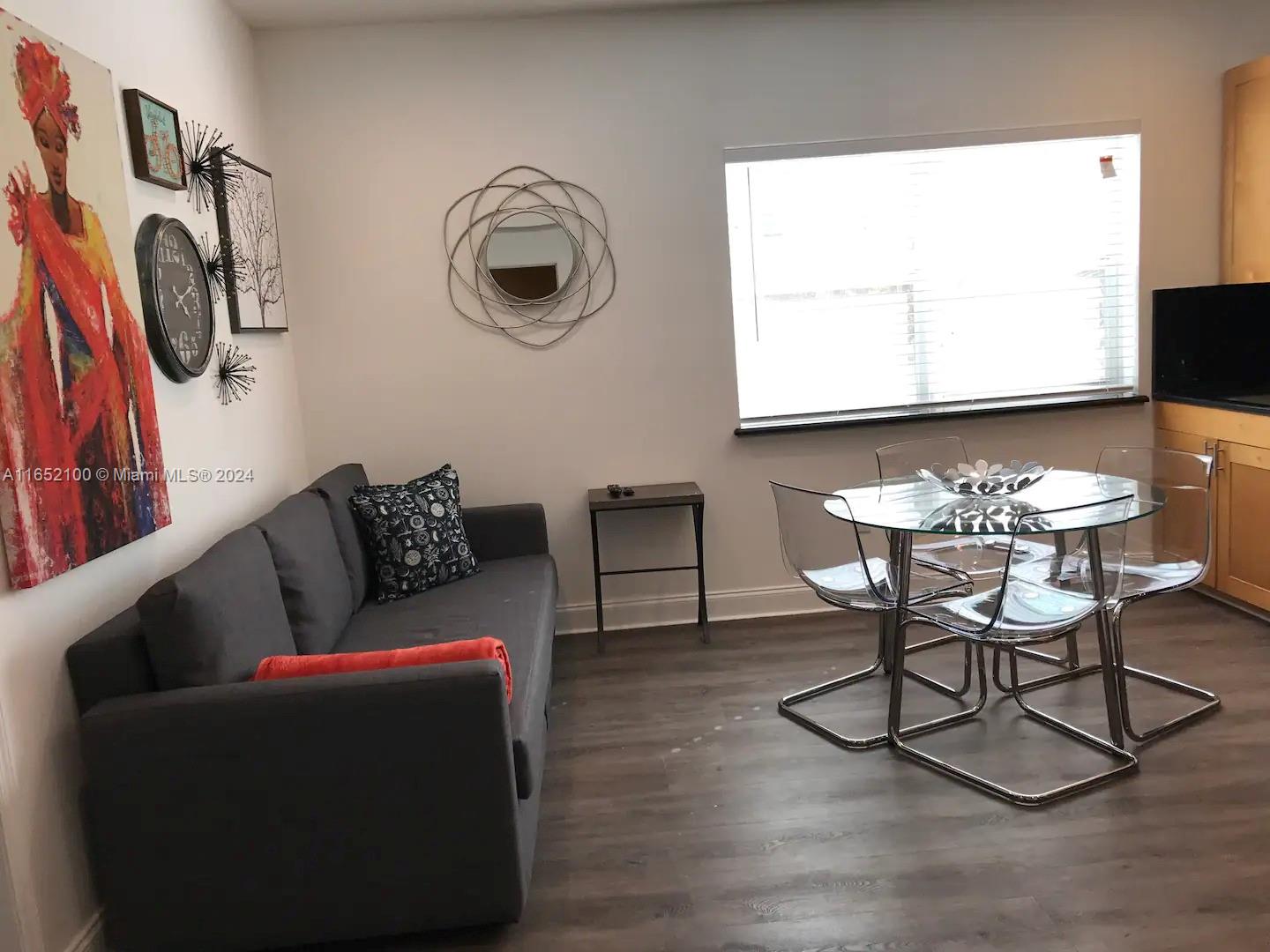 A living and dining area features a gray sofa, glass table, and modern wall decor — 2615 Collins Ave # 24, Miami Beach FL 33140, MIAMI BEACH, FL