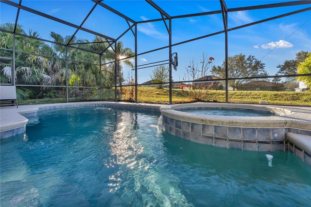 A swimming pool and attached hot tub are enclosed within a screened-in lanai — 620 OLD BRIDGE CIRCLE, DAVENPORT, FL