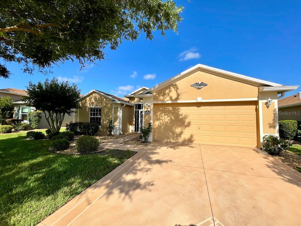A single-story house with a tan stucco exterior, a two-car garage, and a paved driveway — 16026 SW 14TH AVENUE ROAD, OCALA, FL