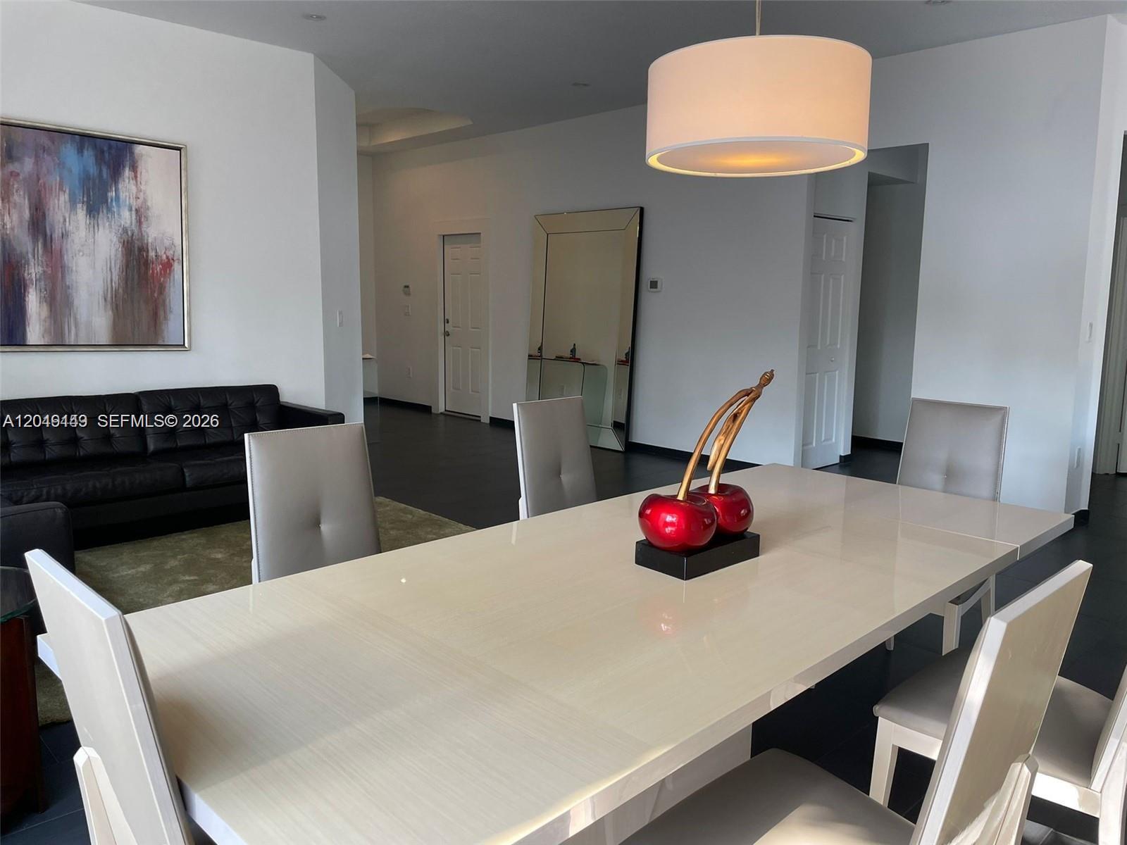 A dining room features a white table, modern chairs, and a large cherry sculpture — 10933 NW 73 TE, Doral FL 33178, DORAL, FL