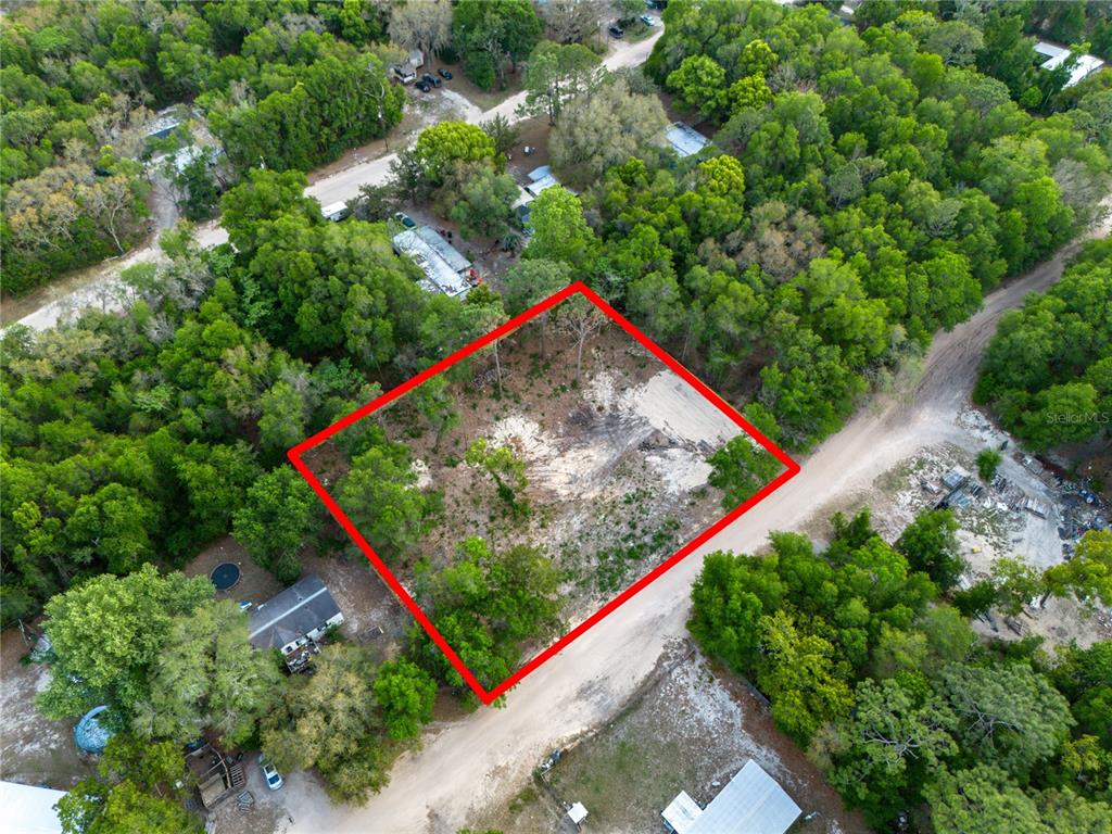 An aerial view shows a vacant, wooded lot outlined in red next to a dirt road — 6397 BAYLOR AVENUE, KEYSTONE HEIGHTS, FL