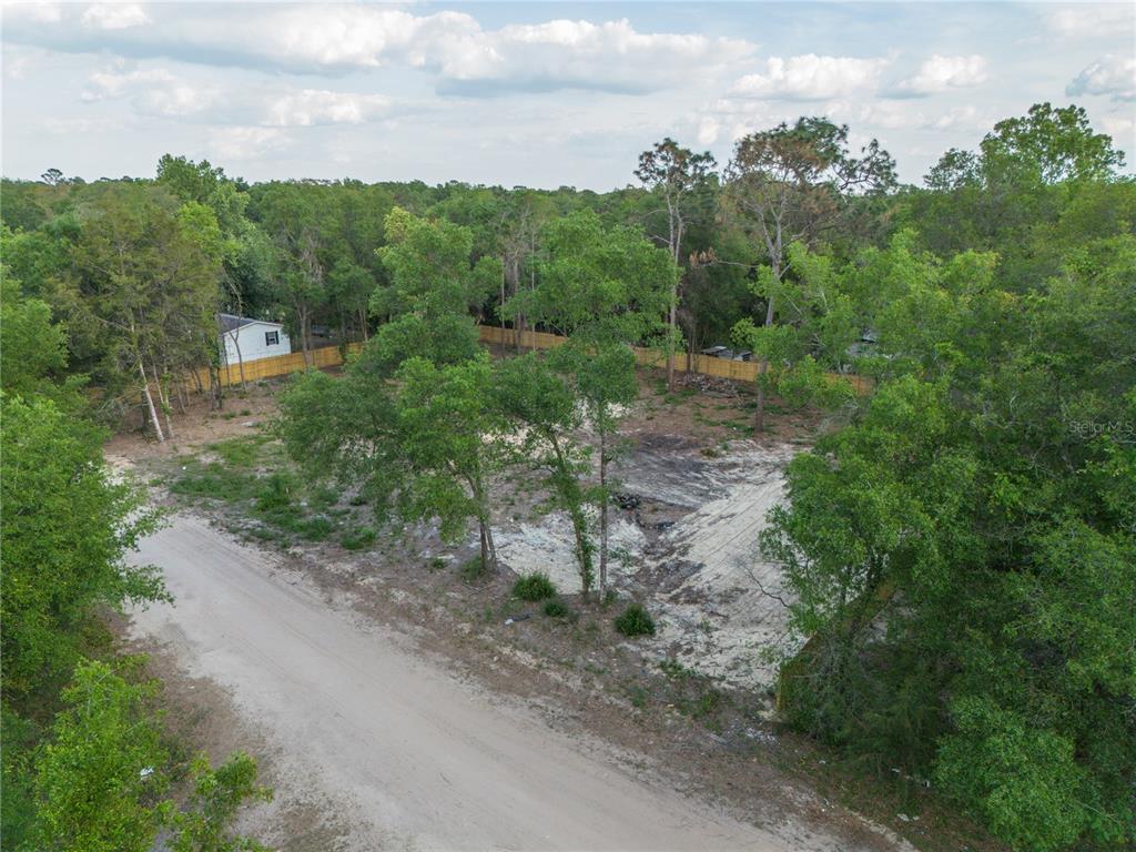 An aerial view shows a cleared, sandy residential lot bordered by trees and a dirt road — 6397 BAYLOR AVENUE, KEYSTONE HEIGHTS, FL