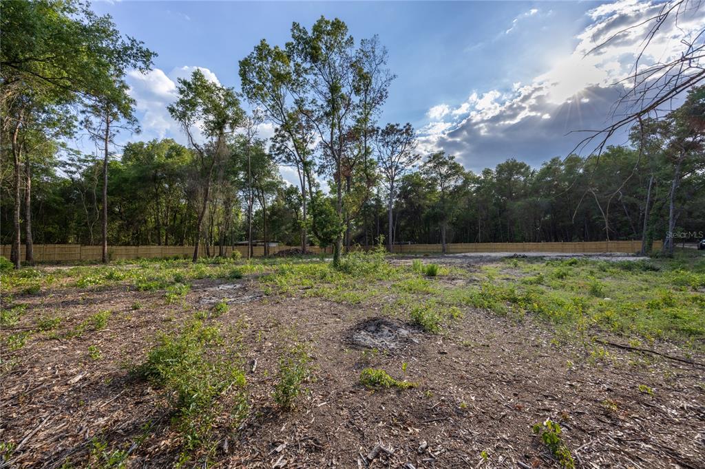 A cleared, vacant lot features sparse vegetation and a wooden fence bordering a wooded area — 6397 BAYLOR AVENUE, KEYSTONE HEIGHTS, FL