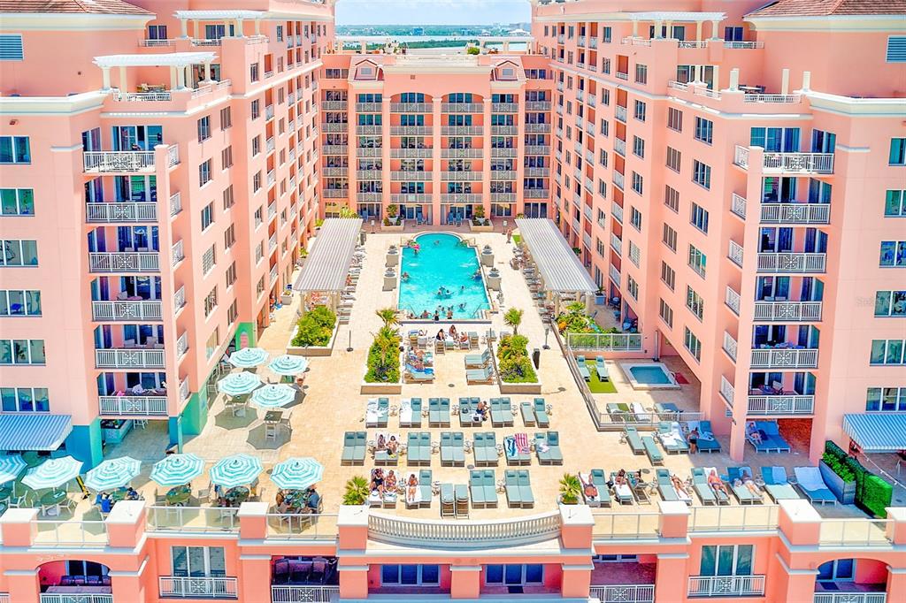 An aerial view of a pink resort building surrounding a central pool and patio area — 301 S GULFVIEW BOULEVARD UNIT 301, CLEARWATER BEACH, FL