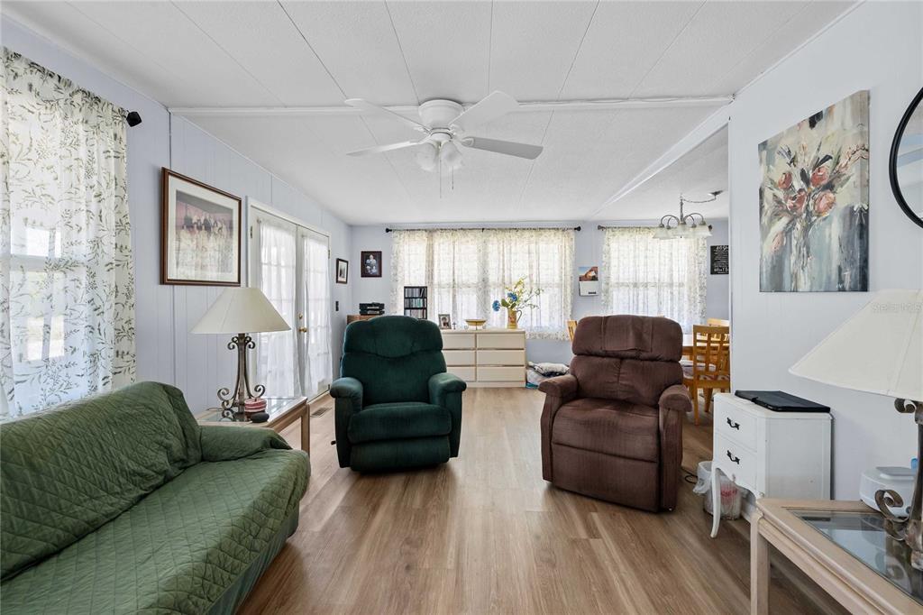 A living room features light wood-look flooring, a ceiling fan, and two recliner chairs — 5301 FLINT STREET, ZEPHYRHILLS, FL