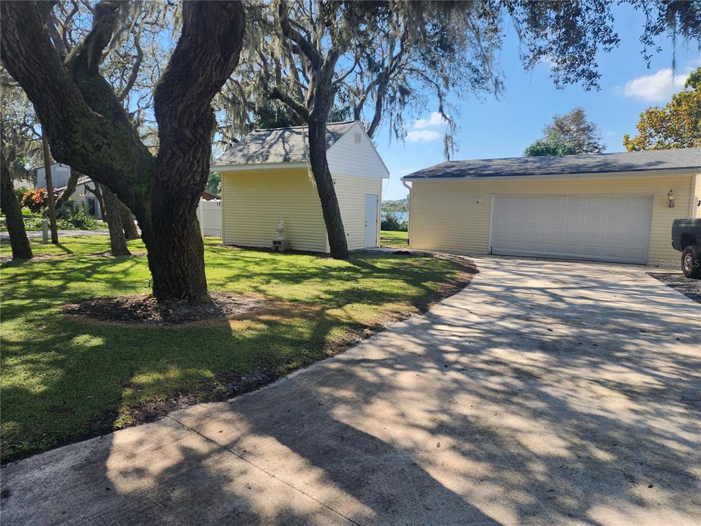 A detached garage and a small shed sit on a grassy lot with large trees — 14902 ARRENA ROAD, WINTER GARDEN, FL