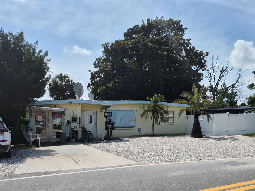 A single-story yellow house with a gravel front yard and a palm tree — 4007 FLAMINGO DRIVE, NEW PORT RICHEY, FL