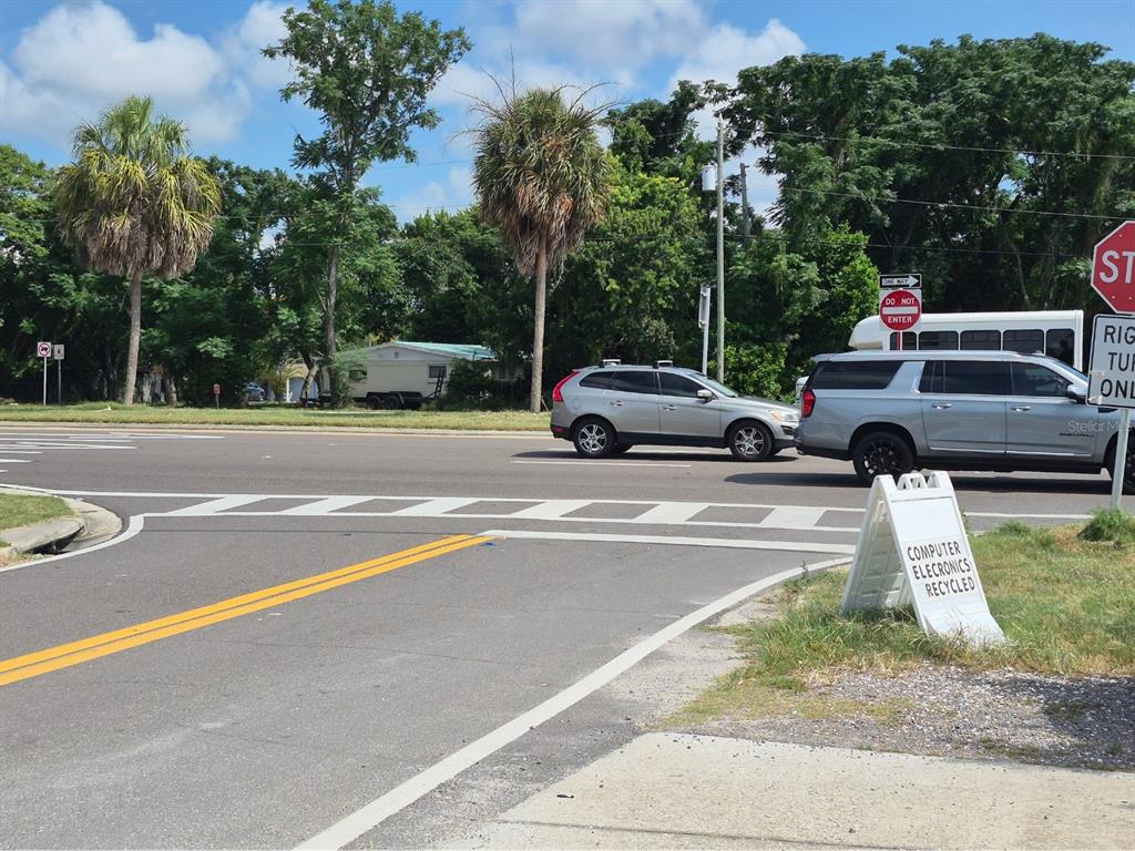 A street intersection features a crosswalk, a silver SUV, a white van, and a sign — 4007 FLAMINGO DRIVE, NEW PORT RICHEY, FL
