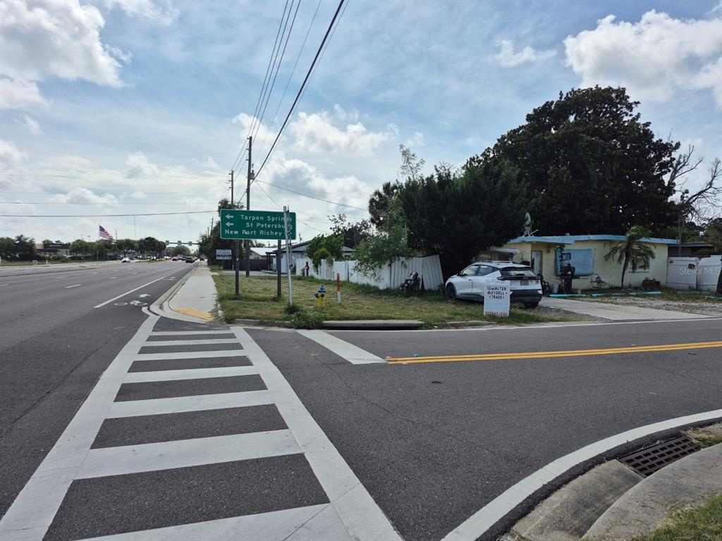 A street-level view shows a crosswalk, a road sign, and a small building with a car — 4007 FLAMINGO DRIVE, NEW PORT RICHEY, FL
