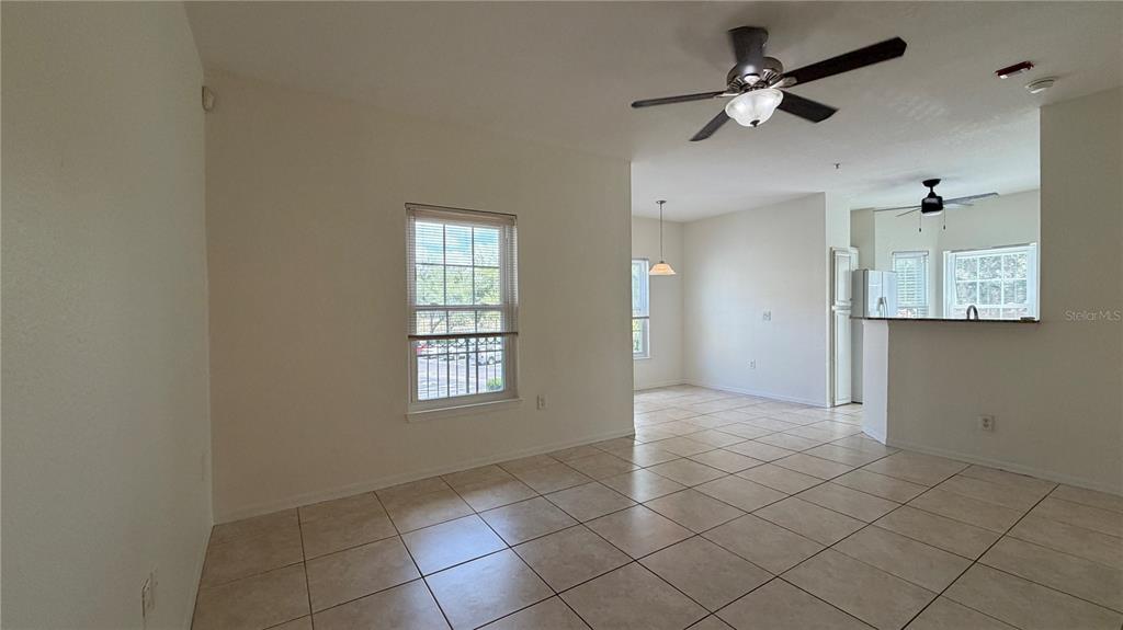 An open-concept living and dining area features light tile flooring and two ceiling fans — 23500 WALDEN CENTER DRIVE UNIT 210, ESTERO, FL