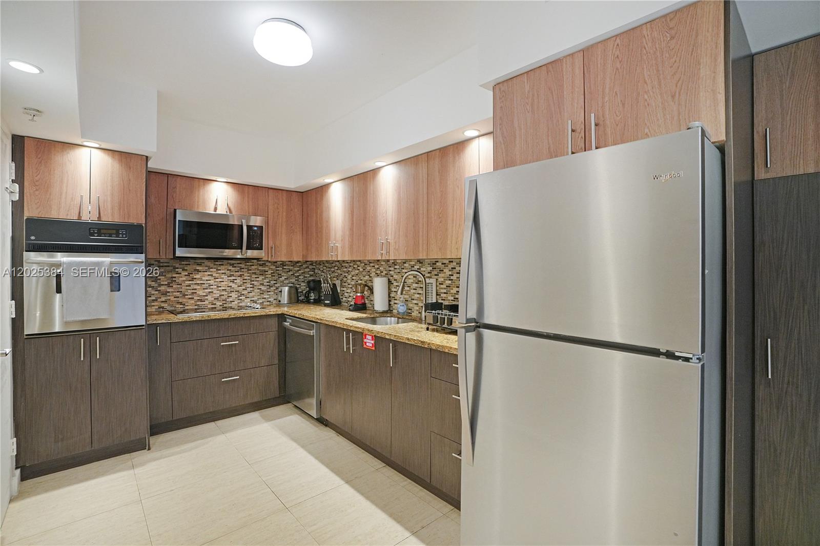 A modern kitchen features two-toned wood cabinetry, stainless steel appliances, and a tiled backsplash — 4001 S Ocean Dr # 3P, Hollywood FL 33019, HOLLYWOOD, FL