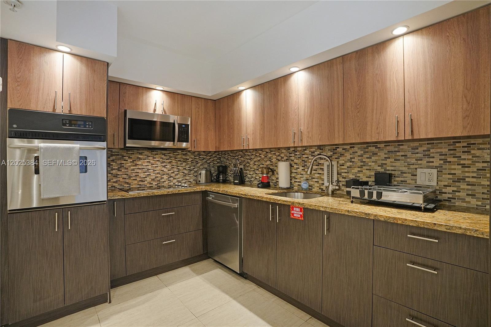 A kitchen features two-toned wood cabinetry, granite countertops, stainless steel appliances, and a tiled backsplash — 4001 S Ocean Dr # 3P, Hollywood FL 33019, HOLLYWOOD, FL