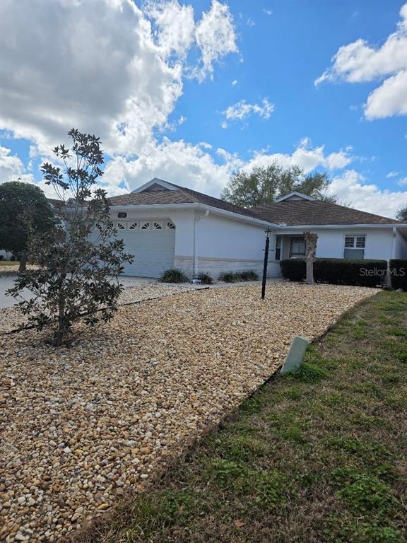 A single-story house with a white exterior, a two-car garage, and a rock-covered front yard — 9028 SW 91ST CIRCLE, OCALA, FL