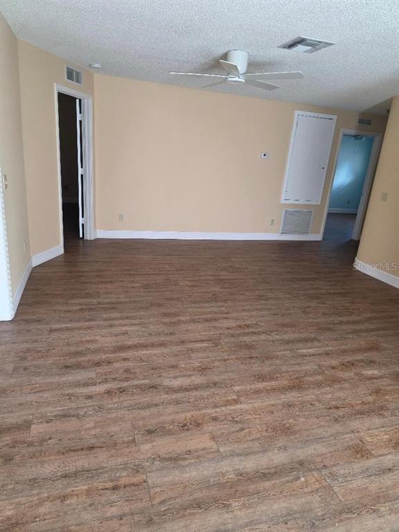 An empty room features wood-look flooring, a ceiling fan, and two doorways — 9028 SW 91ST CIRCLE, OCALA, FL