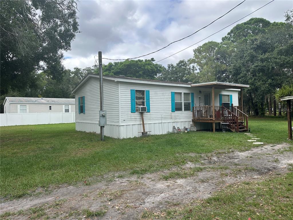 A single-story manufactured home with white siding, blue shutters, and a wooden front porch — 12507 GLENNA AVENUE, TAMPA, FL