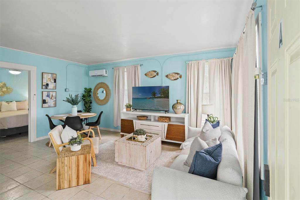 A living room with light blue walls, a white media console, and a beige sofa — 1303 S BERMUDA BOULEVARD, TAMPA, FL
